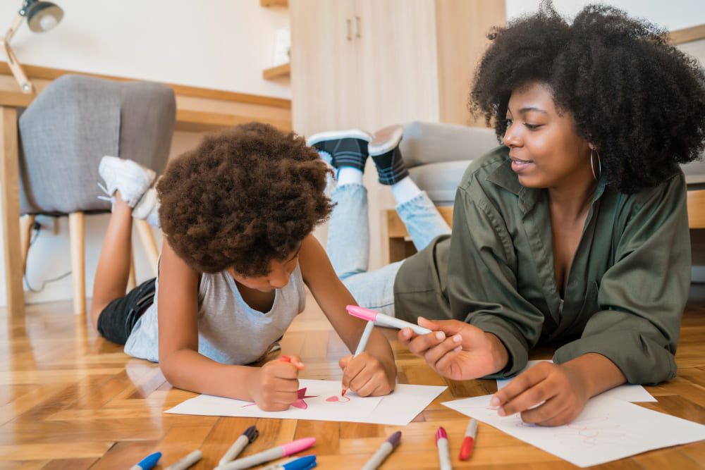 Mãe e filho no chão desenhando em folha juntos