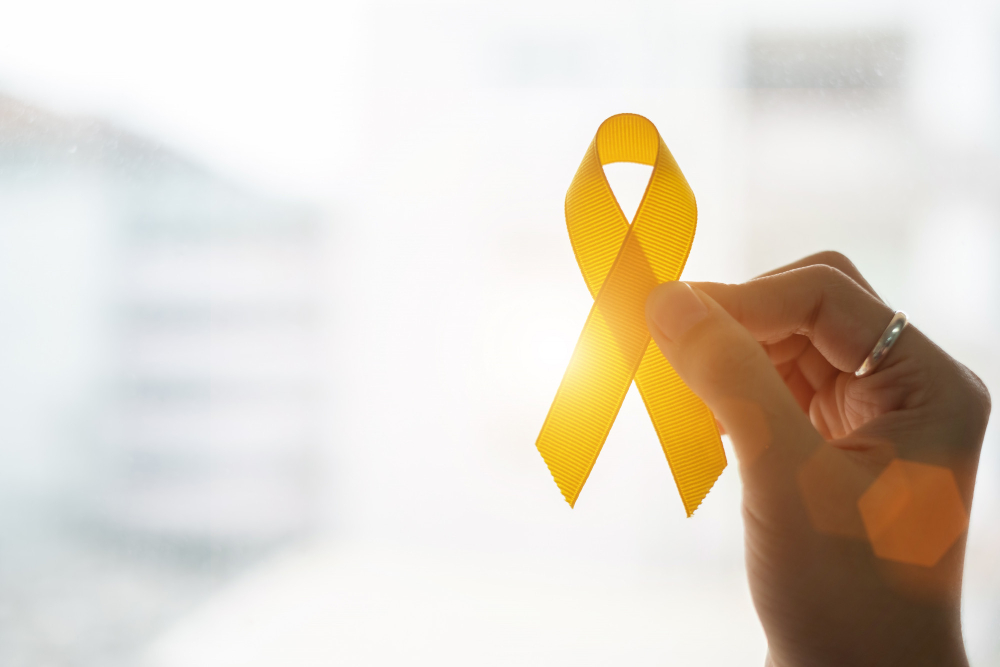 Mão segurando um laço amarelo símbolo da prevenção do suicídio