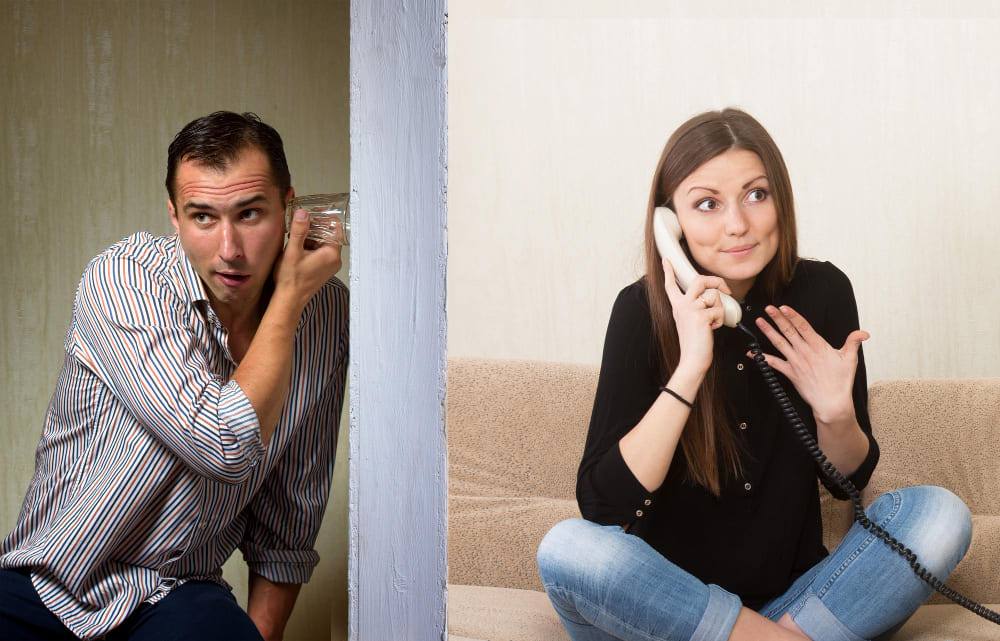 Marido tentando ouvir a conversa da esposa que esta no celular