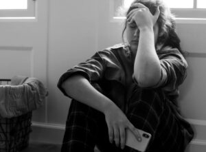 Suicídio: mulher sentada no chão com aparência triste