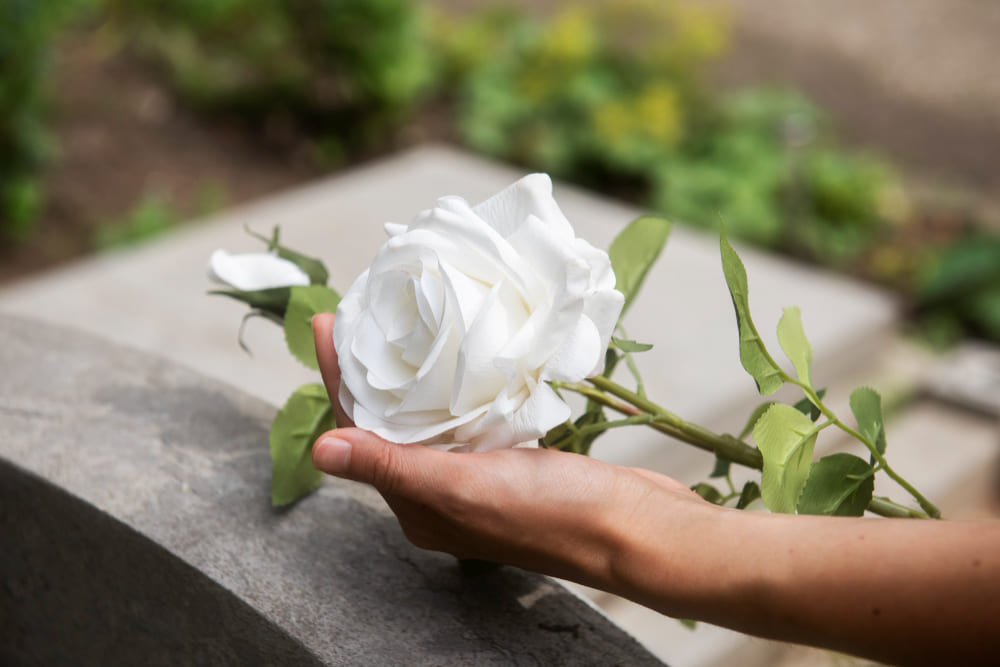 flor branca na frente do túmulo para falar sobre fases do luto
